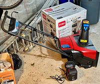 Side view of Toro Power Clear 60V cordless single stage snow blower with original box, battery and charger