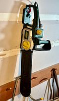 Full view of the Yardworks electric chainsaw hung on a wall showing its compact design, handle, blade cover, and power cord.