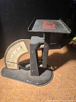 Side view of antique postal scale showing black metal frame and dial.