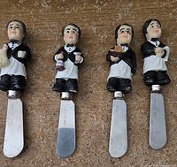 Four butler figurine handles on stainless steel appetizer spreader blades, showing full length and details.