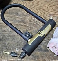 Top view of U-lock and two attached keys on wooden surface.