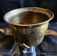 Image showing the planter from a side angle highlighting the hammered brass texture and one of the ornate feet supporting it.