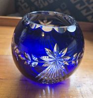 Photo of cobalt blue round crystal bowl showing detailed cut glass floral pattern and scalloped rim.