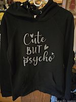 Front view of the black women's hoodie with the phrase "Cute but Psycho" printed in white on front.