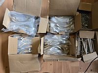 Wide view of six open boxes showing handles in plastic sleeves and one box of screws
