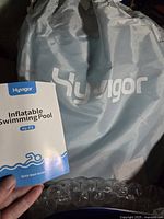 Grey storage bag with Hyvigor logo and instruction manual for inflatable pool.