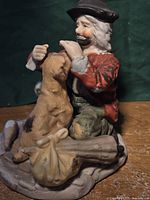 Front view of the hobo figurine sitting with a dog and a bundle on the ground.