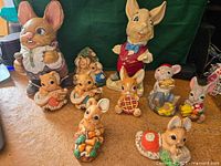 Photo showing multiple rabbit figurines of various sizes and brands arranged together on carpeted floor, including Pepiware Poppa at 8 inches
