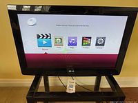 Photo of the LG TV screen powered on showing content selection options including Movie, Photo, Music, Premium, and Settings.