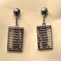 Pair of silver-tone abacus dangling earrings on ball post studs, displayed on a flat surface with a neutral background.