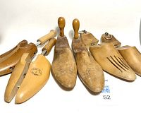Photo of three pairs of foot-shaped wooden shoe forms arranged on white background with visible markings and wear.