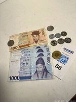 Photo showing four Korean 1000 Won banknotes, one Korean 5000 Won banknote and assorted Asian coins