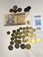 Photo showing one 1 Estonian Kroon paper note and assorted brass and silver-tone coins including Estonian Kroon coins, Finnish Markka, Swedish Krona, and Icelandic Kronur coins arranged on a white background with MaxSold lot identifier.