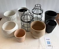 Photo showing two glass bulb containers with metal cages and assorted ceramic and plastic plant pots of varying sizes, placed on a white background.