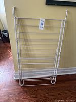 Folded drying rack showing main frame with parallel bars made of white rubber-coated metal.
