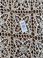 Close-up of the crocheted pattern showing floral and geometric design in cream color with a maxsold lot tag.