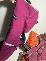 Purple Landsend dog rain jacket with reflective trim held upright, showing fabric detail and shape