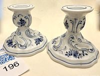 Pair of Hutschenreuther Blue Onion porcelain candlesticks showing front and top views with scroll and floral blue underglaze decoration on white porcelain.