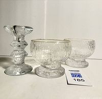 Front view of two textured glass Kekkerit bowls and one Festivo candlestick showing clear textured glass with ripple patterns and organic shapes
