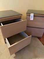 Pair of IKEA Malm bedside tables placed side-by-side, showing front view with both drawers closed on one and open on the other
