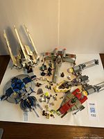 Full view of all Lego Star Wars ships and mini figures displayed on white surface showing the fleet and figures.