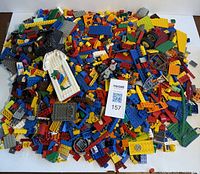 Top down image showing a large pile of assorted loose Lego bricks and parts in multiple colors including red, yellow, blue, black, green, and grey.