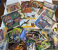 Top view of multiple Lego instruction manuals spread out, featuring Bionicle, Mars Mission, System, Dinosaur, and others