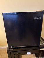 Front view of black Magic Chef mini fridge with logo visible on door.