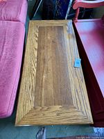 Top view of rectangular coffee table with oak beveled edges and walnut center panel between pink couch and red furniture.