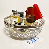 Perfume bottles arranged inside a clear cut glass bowl with a silverplate rim, showing variety of brands and styles.