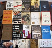 Photo showing all 19 books laid flat on surface, covers facing up, including titles on evolution, philosophy, and political thought.