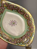 Close-up of the elliptical porcelain dish showing the pink flowers and gold edging.