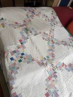 Full view of the quilt draped over furniture showing patchwork design and green edging.