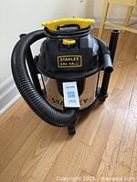 Front view of Stanley wet/dry shop vacuum with extension hose wrapped around top handle, showing brand and motor specs.