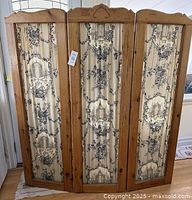 Front view of three wooden panels with fabric inserts showing toile garden pattern.