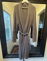 Grey waffle weave Turkish cotton bathrobe hanging on black framed mirror, showing full front with sash and collar visible