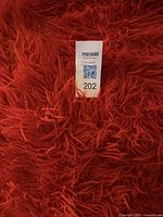 Close-up detail of the long orange wool fibers in the shag rug showing dense pile texture.