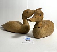 Front side view of two unpainted vintage wooden duck decoys showing glass eyes and overall shape.