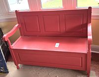 Front and side view of coral pink wooden bench showing carved panels and rounded armrests