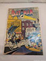 Front cover of 1957 Batman No. 108 comic book from DC Comics showing color cover art with Batman riding a bicycle and Batman and Robin in a car.