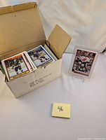 Box containing multiple 1990 O-Pee-Chee NHL hockey cards with one card displayed on a stand.