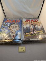 Two stacks of MAD magazines with visible colorful cartoon covers, one showing the 400th issue, the other featuring a caricature of Slim Shady (Eminem) on the cover.