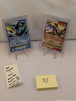 Two Pokemon cards (Empoleon LV.X and Infernape LV.X) in protective cases displayed upright on stands.