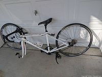 Full side view of white 2016 Miele Svelto RR women's road bike with rear wheel installed and front wheel removed, lying on side.