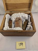 Wooden box containing three antique hand carved soapstone seal stamps wrapped in cushioning paper