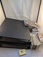 Overview of the lot showing two large black binders stacked plus multiple stacks of loose cards and cards in plastic sleeves.