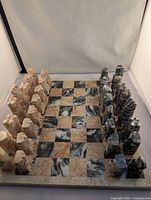 Full view of complete onyx chess set with pink and black pieces arranged on matching onyx board with alternating squares reflecting natural stone patterns.