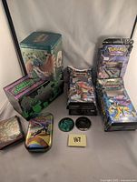 View showing the bulk cards in the deck boxes, collectible tins featuring Pokemon artwork, and two collectible coins on display.