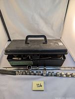 Closed black plastic toolbox with handle next to socket rails and some sockets arranged outside.