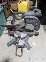 Side view of Rona mitre saw showing handle, blade, and base with angle adjustment.